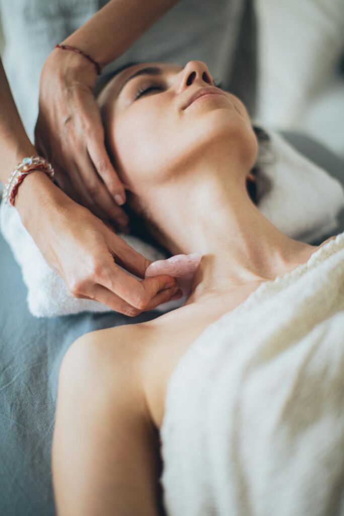Woman receiving a relaxing gua sha massage in a calm spa setting for wellness and beauty.